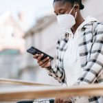 Mulher usando o celular para navegar na internet ao lado de uma bicicleta