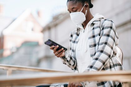 Mulher usando o celular para navegar na internet ao lado de uma bicicleta