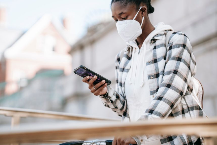 Mulher usando o celular para navegar na internet ao lado de uma bicicleta