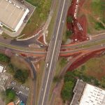 Vista aérea de um entroncamento rodoviário em Londrina, no Paraná, com veículos e áreas urbanizadas ao redor.