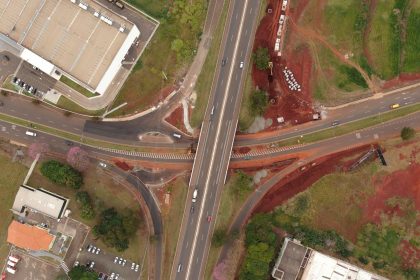 Vista aérea de um entroncamento rodoviário em Londrina, no Paraná, com veículos e áreas urbanizadas ao redor.