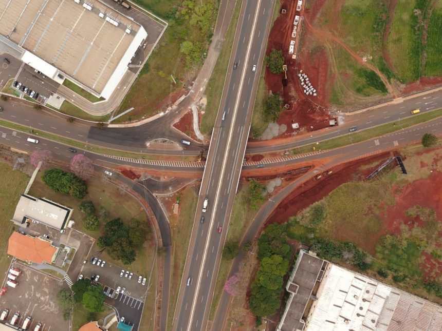 Vista aérea de um entroncamento rodoviário em Londrina, no Paraná, com veículos e áreas urbanizadas ao redor.