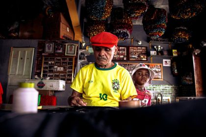 Homem idoso e menino criam uma peça artística juntos em uma oficina colorida.